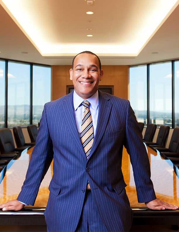 Photography Portrait on location of African American CEO smiling in pinstripe suit in front of conference table Newport Beach 